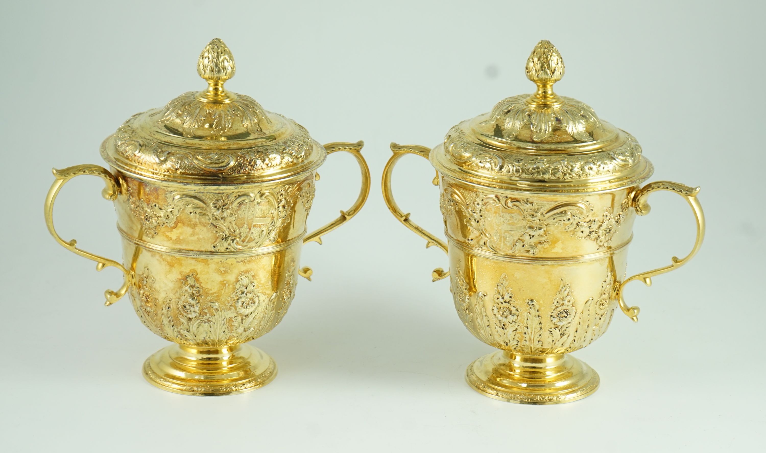 A good pair of George II embossed silver gilt two handled pedestal cups and covers, by Benjamin Gignac